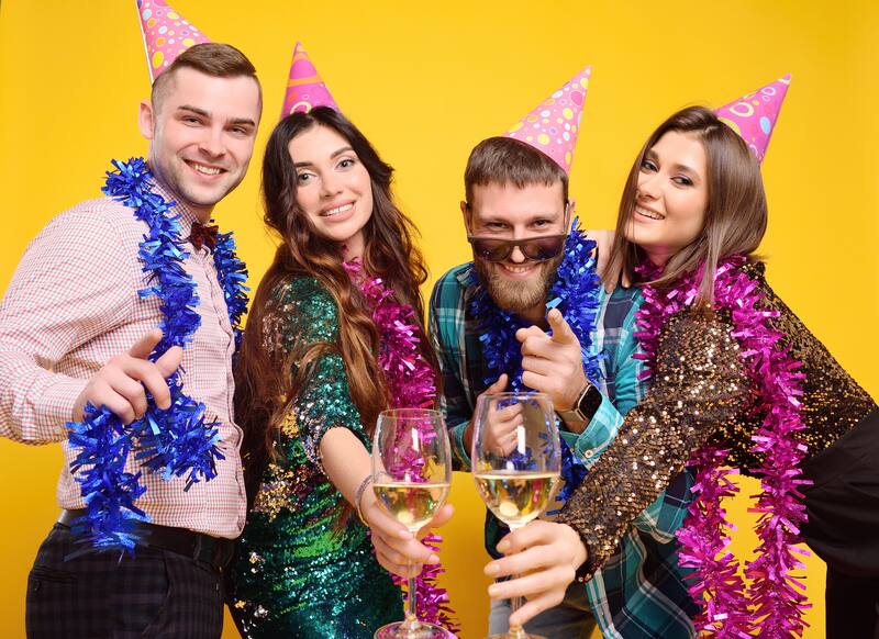 Group of friends celebrating with party hats and champagne